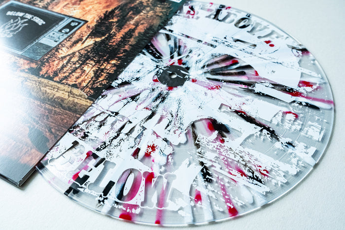 A close-up of a clear The Bar Stool Preachers Below The Static Vinyl LP with white and red splatter, partially inside an album cover featuring trees. Ideal for collectors seeking reimagined tracks on presale vinyl.