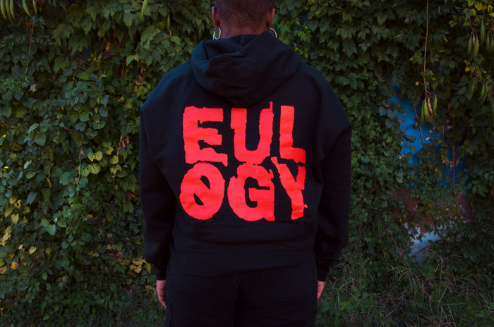 A person faces away from the camera, wearing a black Counterparts hoodie featuring EULOGY in bold red letters.