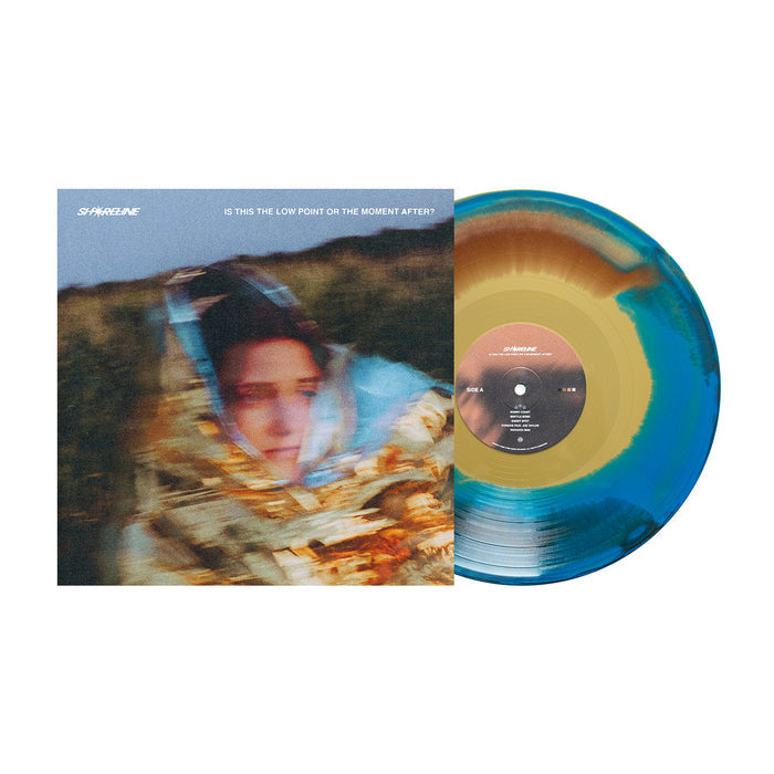 A limited edition marbled Gold/Blue/Brown Vinyl LP by Shoreline features the album "Is This The Low Point Or The Moment After?" with cover art of a blurred figure in a reflective blanket. Now available for presale.