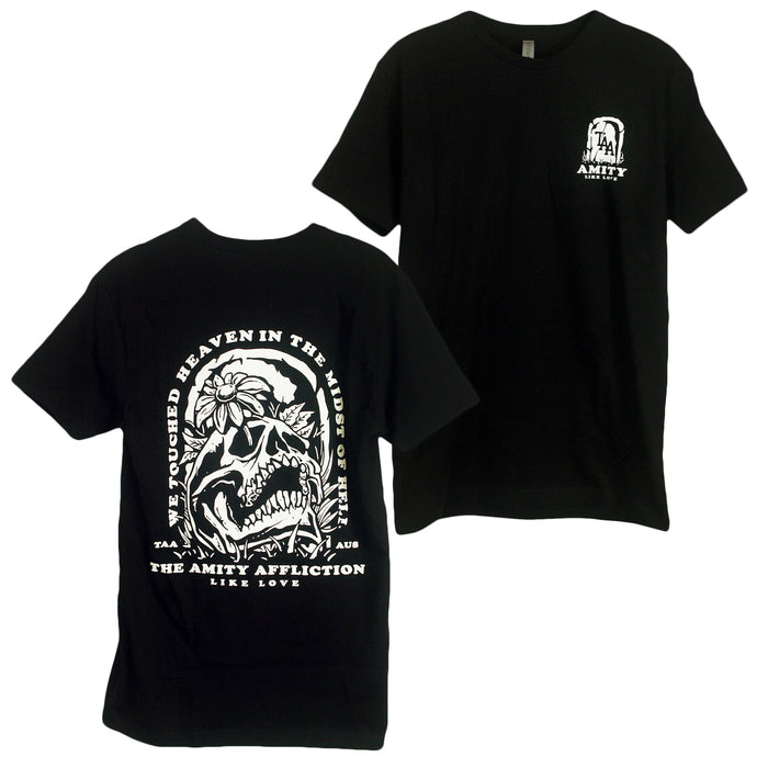 The Amity Affliction black T-shirt features a small white logo on the front left chest and a large skull with flowers graphic on the back, with text: WE TOUCHED HEAVEN IN THE MIDST OF HELL and LIKE LOVE.