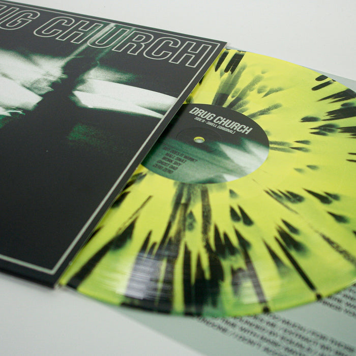 A Canary Yellow Vinyl with black streaks from Drug Church is partially pulled from a black and green Swell album cover, with the album title and tracklist partly visible—a must-have for collectors or fans during the Album Presale.