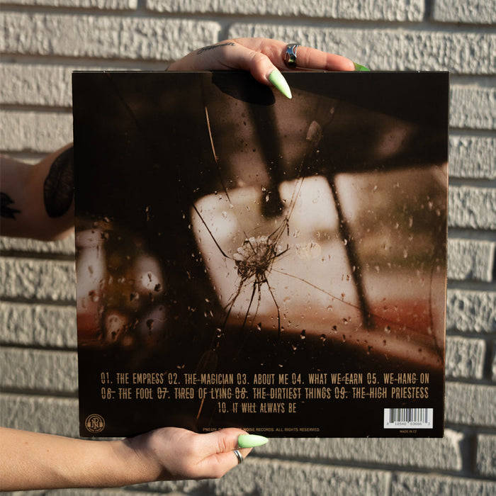A person with mint green pointed nails holds The Early November Eco Mix Vinyl, featuring a cracked glass design, against a white brick wall. The presale tracklist (#1–10) is printed in yellow at the bottom of the LP cover.